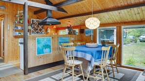 A wooden interior with a dining area, wooden beams, a large window, and a ceiling with skylights. - "Herlek" - 200m from the sea by Interhome (Knebel)