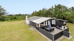 Uma cabana moderna com área de pátio, uma janela grande e vista para a paisagem ao redor.