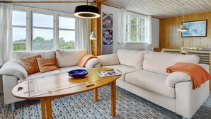 Uma sala de estar aconchegante com sofá, mesa de centro e área de jantar com mesa e cadeiras.