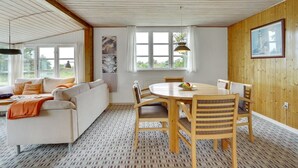 Uma sala de estar acolhedora com um sofá, uma mesa de jantar com cadeiras e um chão estampado.