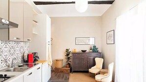 Une cuisine compacte avec des meubles blancs, un pare-feu noir et blanc, un plan de travail en bois et un luminaire moderne.