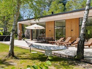 Una casa moderna con un patio que incluye una mesa, sillas y una hamaca.