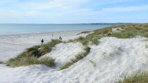 Une plage avec des dunes de sable et un ciel dégagé.