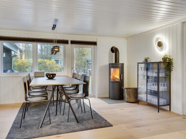 Enjoy meals in the central dining area with a round table and six chairs, offering a view of the outdoors.