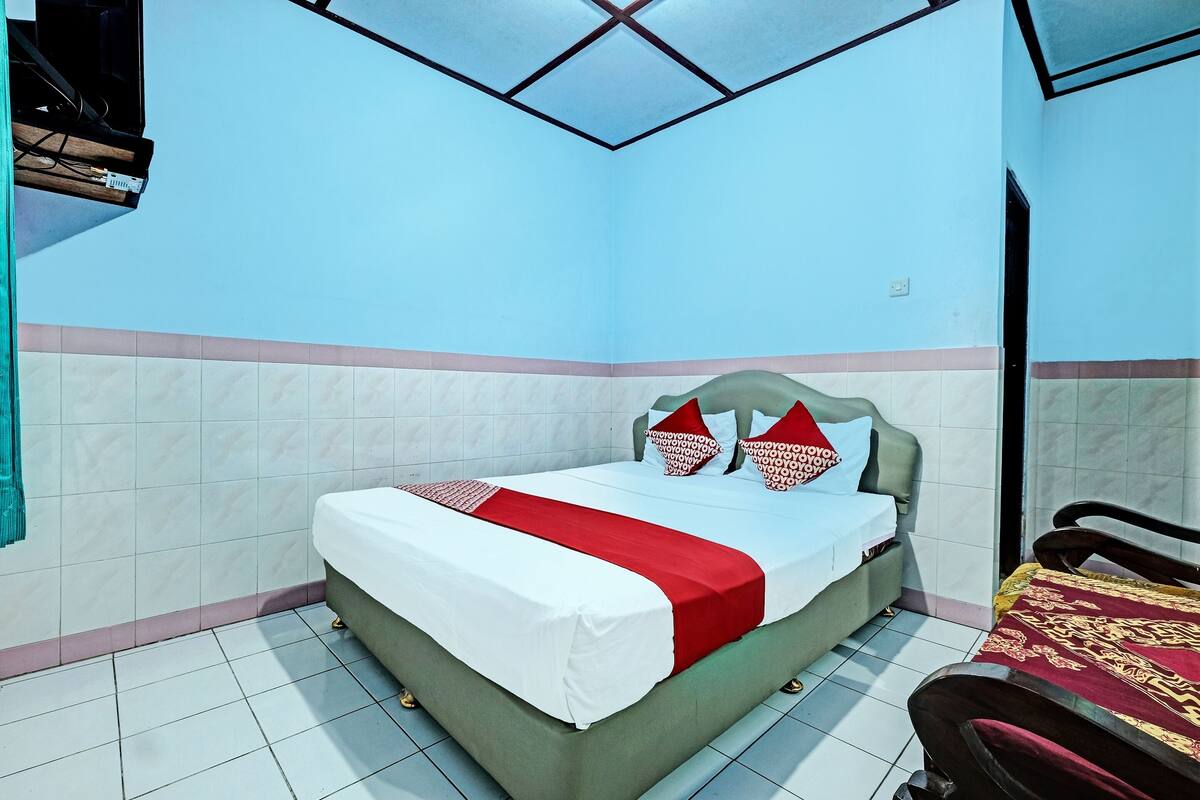 A room with a bed, a sofa, and a TV mounted on the wall.