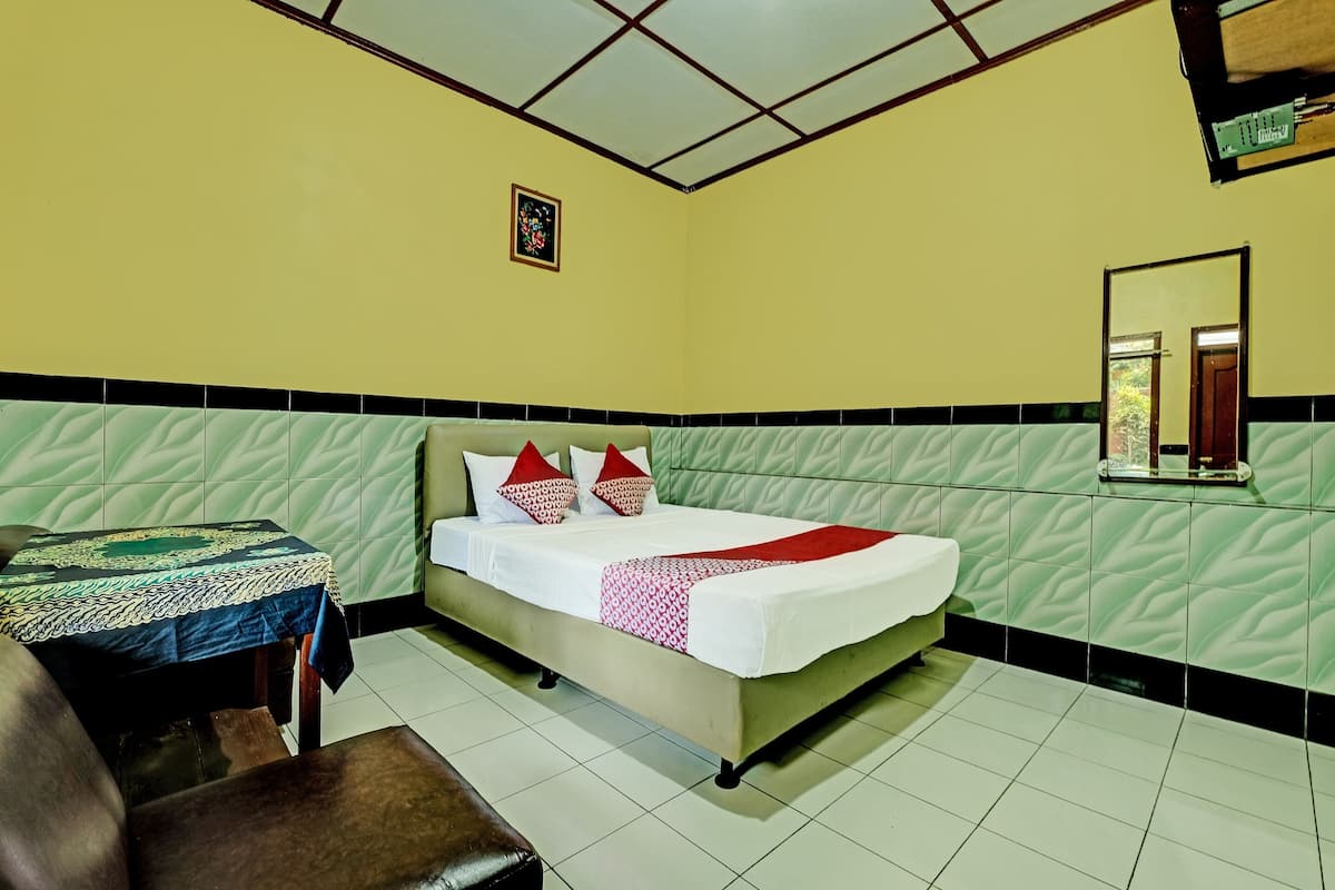 A hotel room with a bed, a table, and a bench.