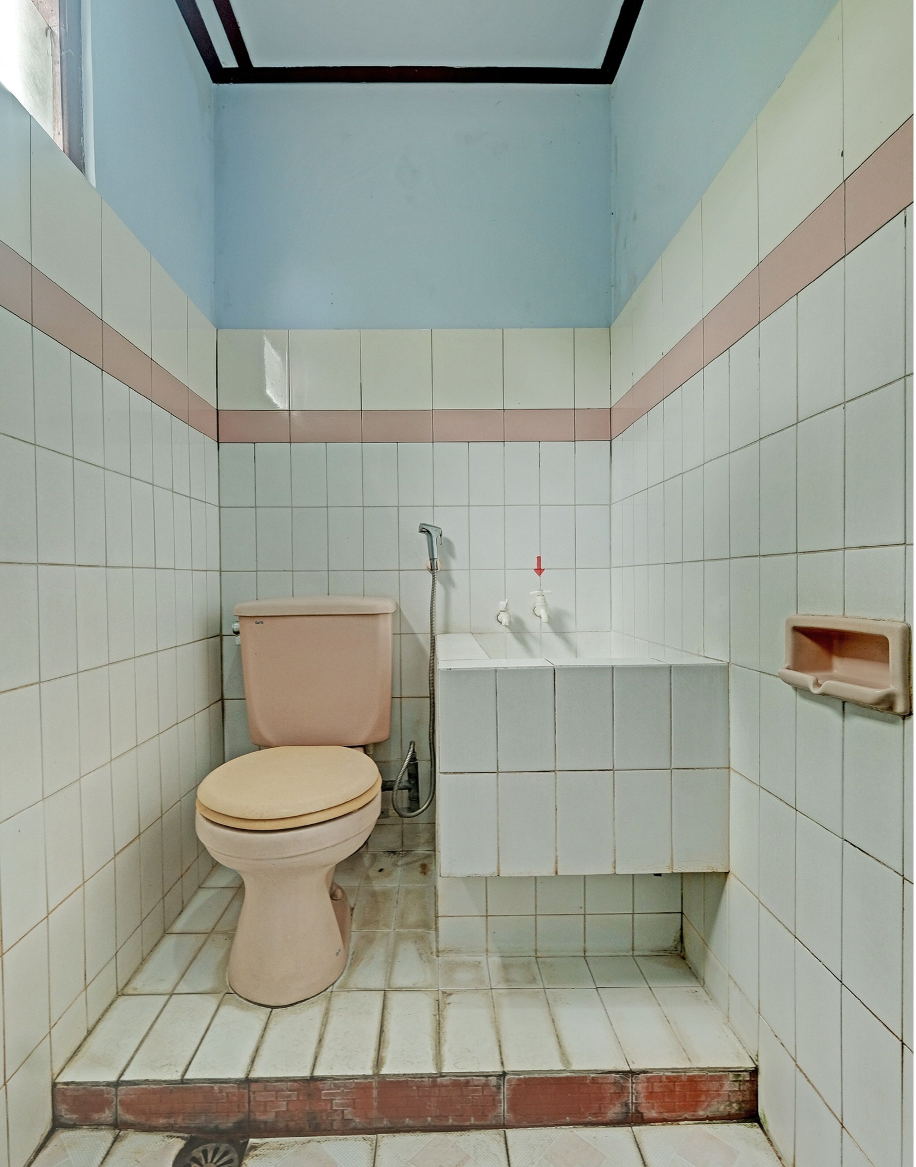 A small, tiled bathroom with a toilet, a sink, and a shower.