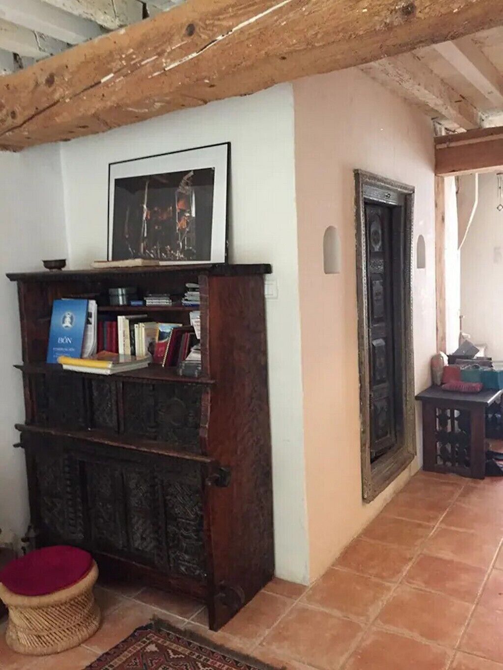 Una habitación con una estantería de madera, un cuadro enmarcado y una puerta tradicional.