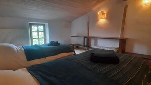 Una habitación con dos camas, una ventana, un radiador y un estante fijado a la pared.