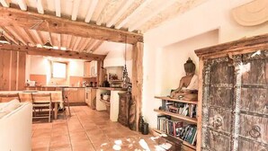 Un interior rústico con vigas de madera a la vista, una zona de cocina, una mesa de comedor y una estatua de Buda.
