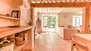 Una cocina con vigas de madera, suelo de baldosas y vistas a un espacio exterior.