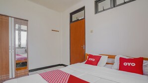 A hotel room with a bed, a wardrobe, and a window. - OYO 90352 Villa Agape 2 (Cipanas)