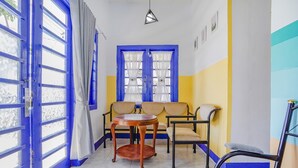A room with a blue door, a round wooden table, two beige sofas, and a black chair. - OYO 90352 Villa Agape 2 (Cipanas)