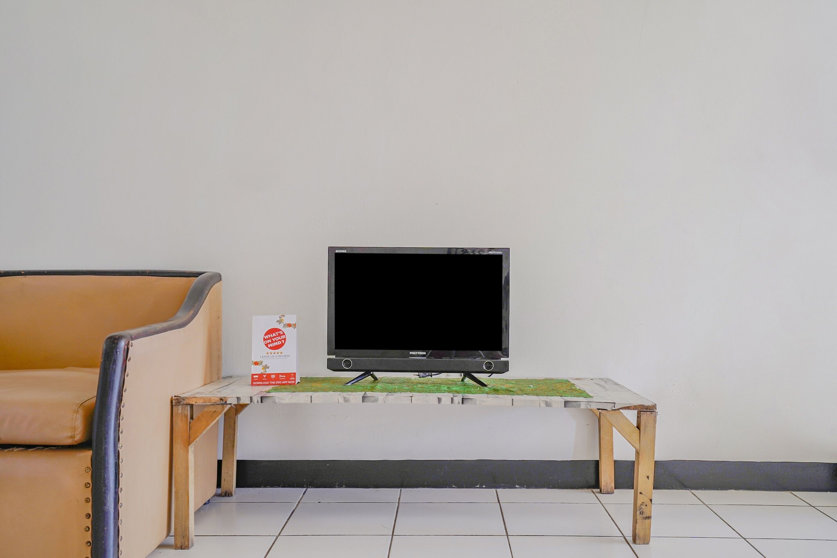 A room with a television on a wooden stand, a small table with a box, and a chair.