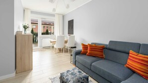 Una sala moderna con un sofá gris, un mueble de madera y un otoman estampado.