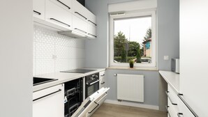 Una cocina moderna con armarios blancos, horno empotrado y ventana con vistas al exterior.