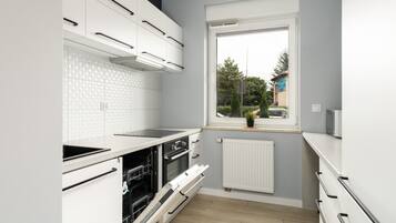 A modern kitchen with white cabinetry, a built-in oven, and a window with a view of the outside.