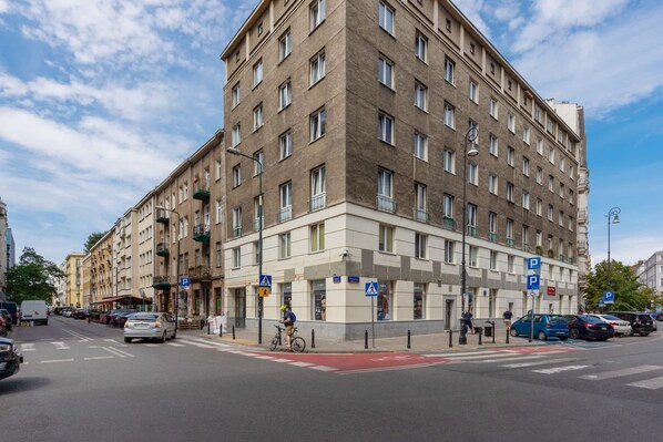 A multi-story building with a corner entrance, a bike lane, and a pedestrian crossing.