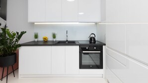 A modern kitchen with white cabinets, a black countertop, a built-in oven, and a sink.