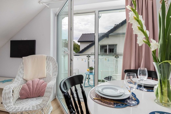 A beautifully set dining table with floral decor, elegant tableware, and a cozy seating area nearby.