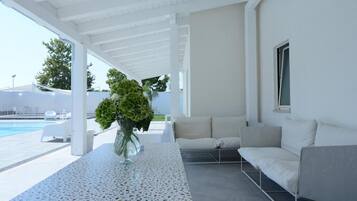 Relax by the pool in a serene, contemporary space with a stylish sofa and lush greenery.