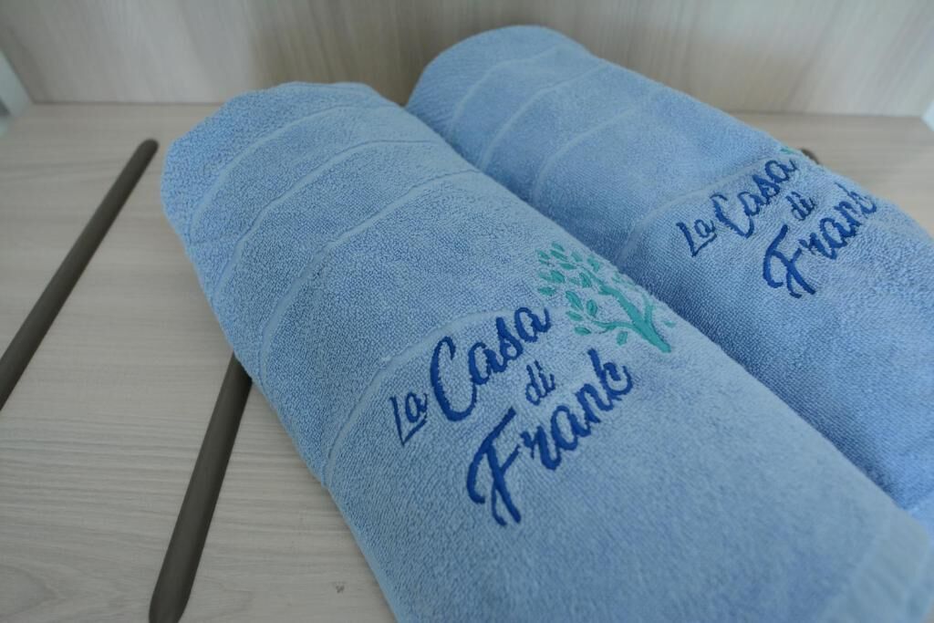 Two rolled-up towels with embroidered text.