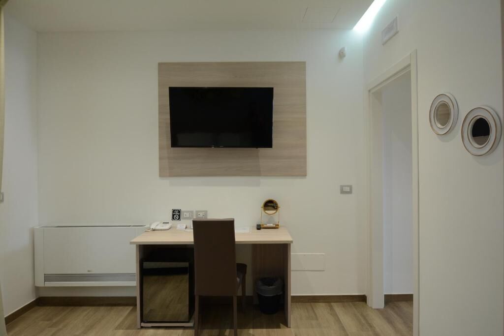Una habitación pequeña y moderna con escritorio, silla y televisor montado.