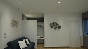 Una sala moderna con un sofá de color oscuro, una puerta blanca y una pared decorada con platos.