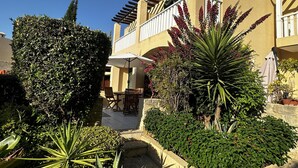 Une cour dotée d’une pergola, d’un espace salon extérieur et de diverses plantes.
