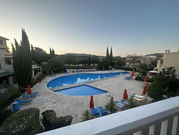 A swimming pool with lounge chairs and umbrellas, surrounded by trees and buildings. - Paradeisos is a Stunning 2-bed House in Polis (Polis)