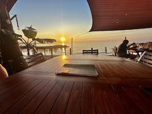 A wooden deck with a table and benches, overlooking the ocean at sunset. - Paradeisos is a Stunning 2-bed House in Polis (Polis)