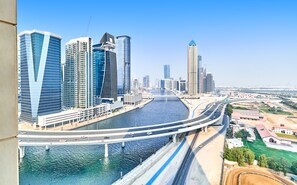 A high-rise building with a modern design, a river running through the city, and a bridge connecting different parts of the city. - bnbme | Noora Tower | 2 BDR (Dubai)