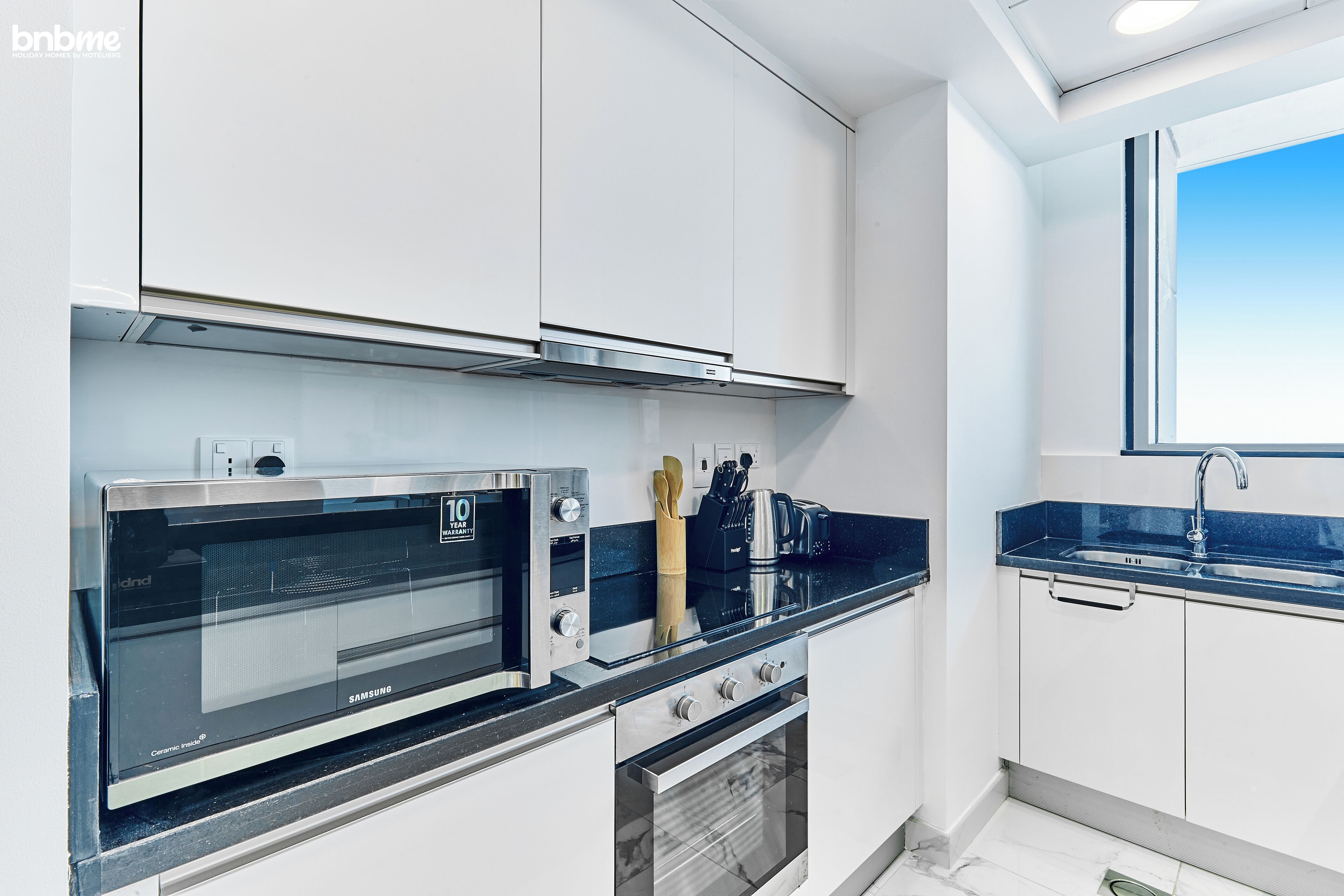 A modern kitchen with white cabinets, a stainless steel microwave, and a built-in oven.