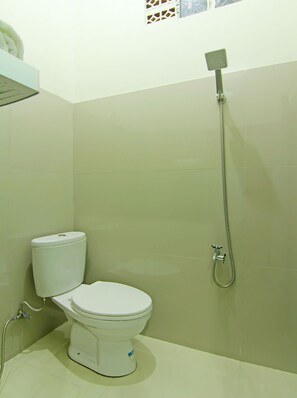 A small bathroom with a toilet, a shower, and a window.
