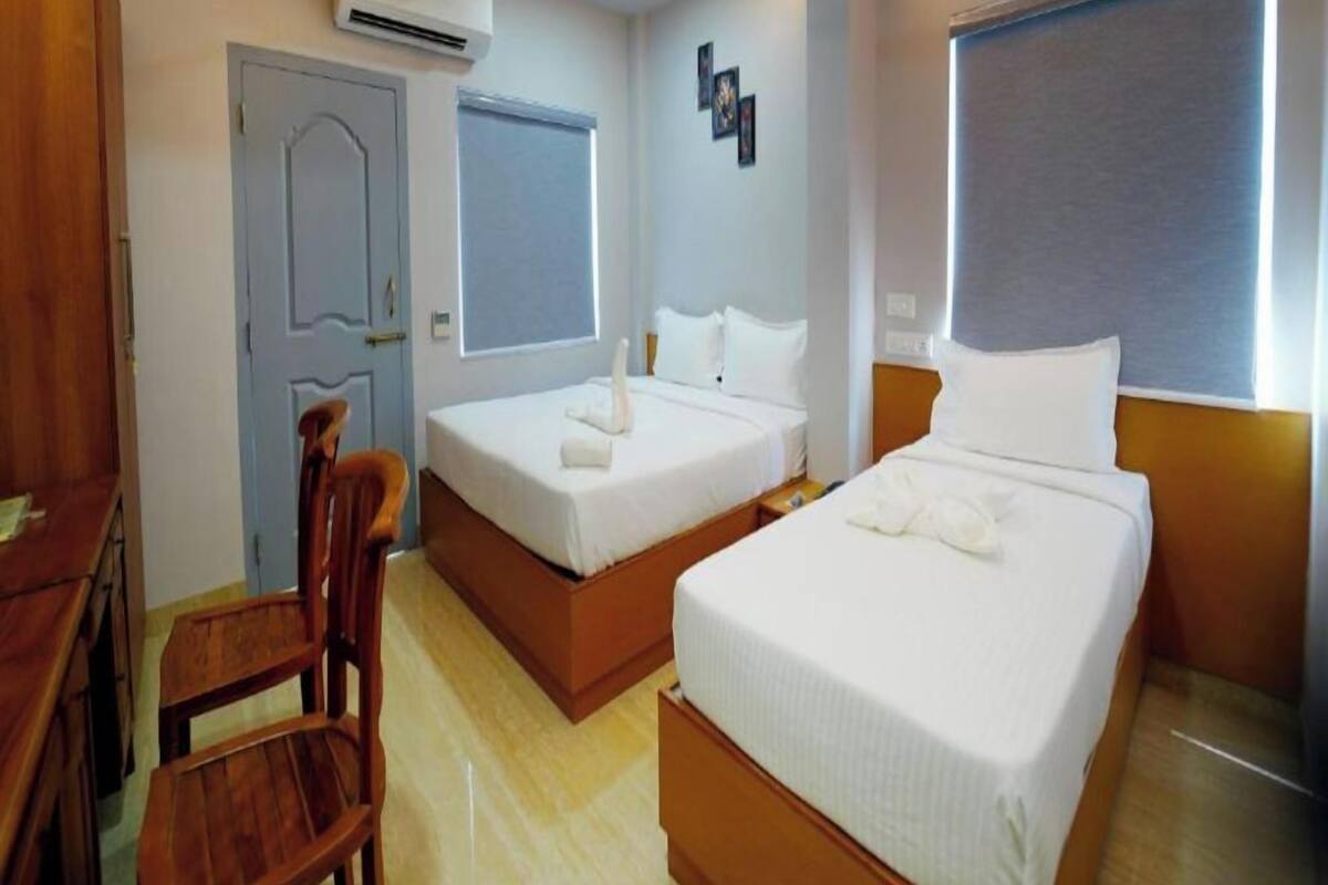 Habitación de hotel con dos camas, un escritorio, una silla, aire acondicionado y ventilador de techo.