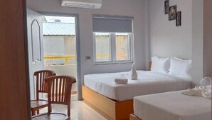 A hotel room with two beds, a wooden chair, and a window with blinds. - Moshis Nest (Madurai)