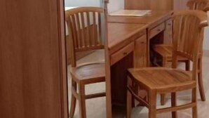 A room with a wooden dining table, four chairs, and a wooden wardrobe. - Moshis Nest (Madurai)