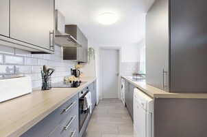 Una cocina moderna con armarios grises, encimera de madera, horno empotrado y lavavajillas.