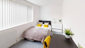 A bedroom with a bed, white bedside tables, a radiator, a window with blinds, and a ceiling light. - Perfect Location for City Centre-university (Sunderland)