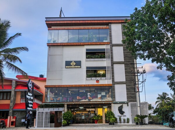 A multi-story hotel with a modern design, featuring large glass windows and a prominent sign for Hotel Golden Riviera.