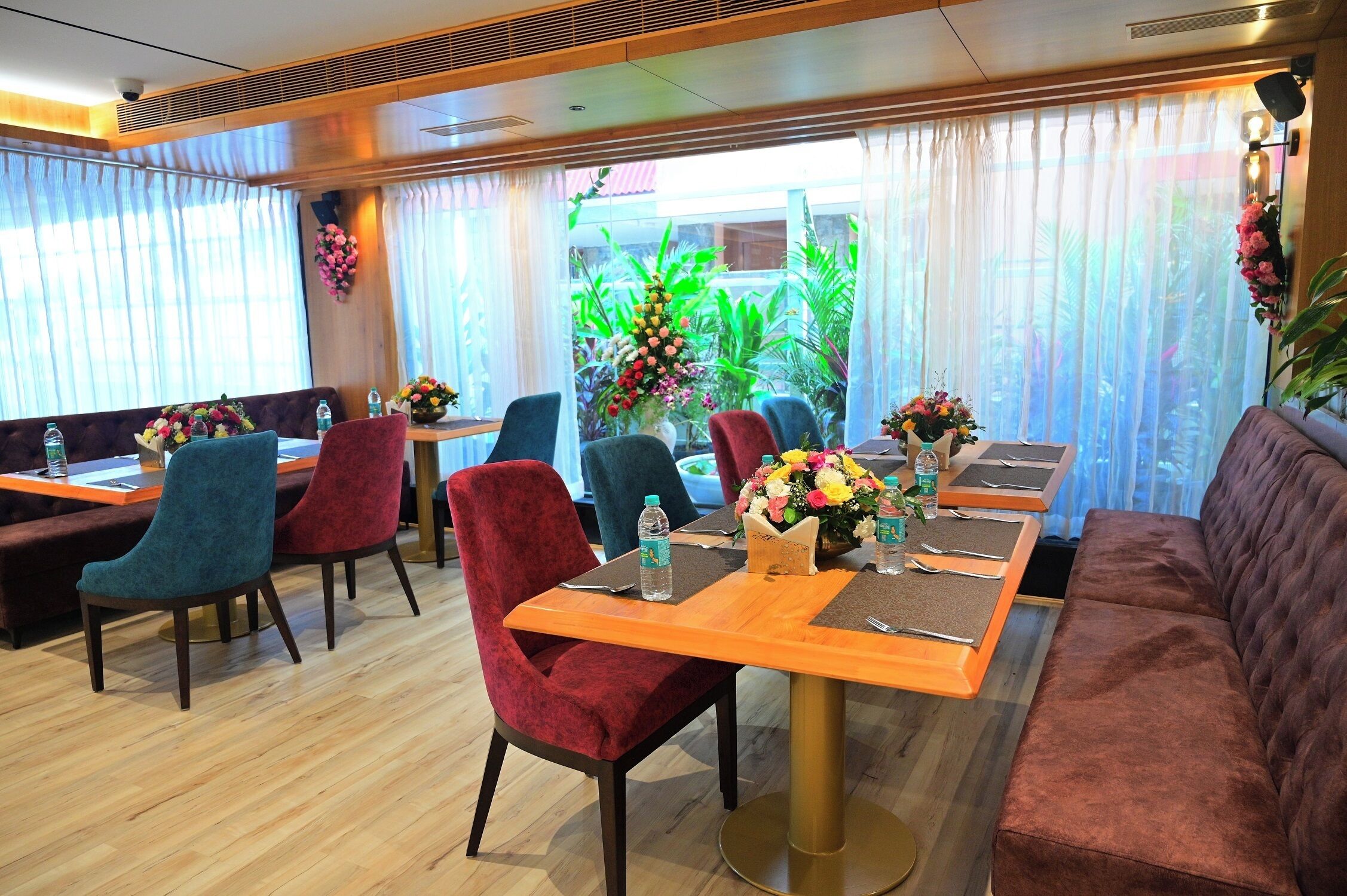 A hotel dining area with a long wooden table, multiple chairs, and a sofa.