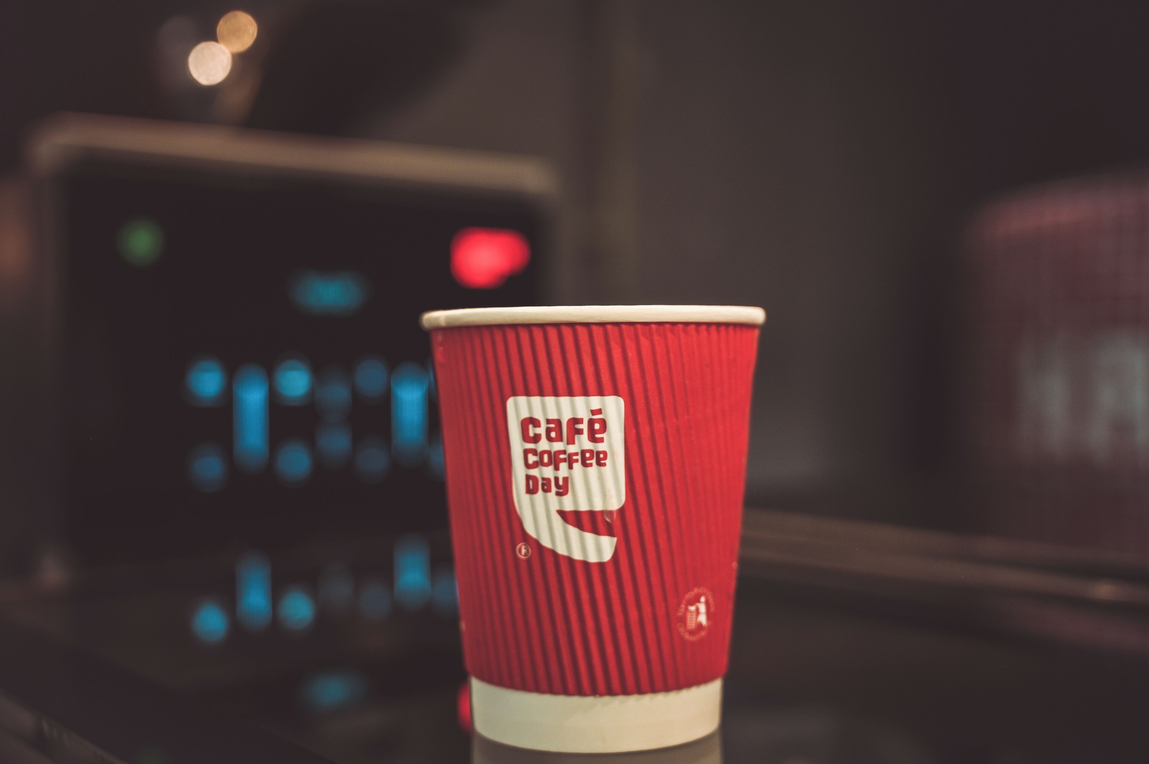 Un vaso de papel rojo con la leyenda 'Café Coffee Day' impresa.