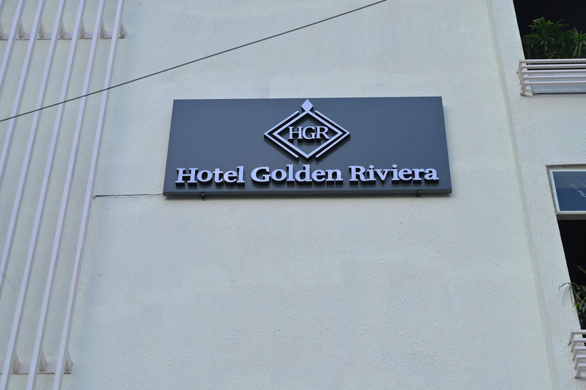 A sign for Hotel Golden Riviera with a logo and name.