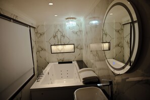 A modern bathroom with a freestanding bathtub, a large mirror, and marble walls.