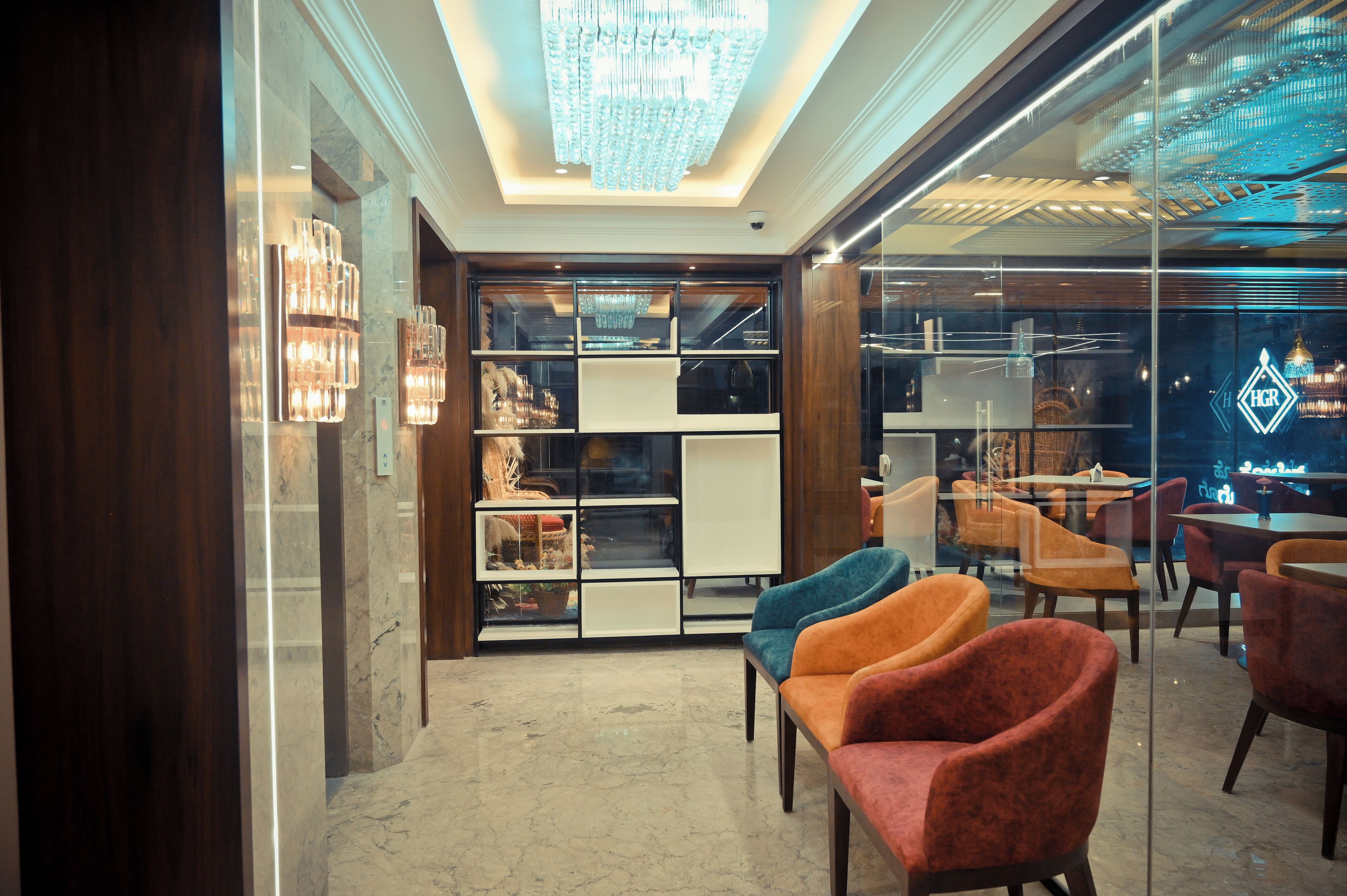 Un intérieur moderne avec une cloison en verre, un lustre et des espaces aménagés pour s’asseoir.