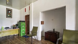 Ein Zimmer mit Schreibtisch, zwei Stühlen, einem Schrank und einer Tür zu einem anderen Raum.