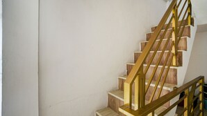 Eine Holztreppe mit goldener Handlauf und weißen Wänden.