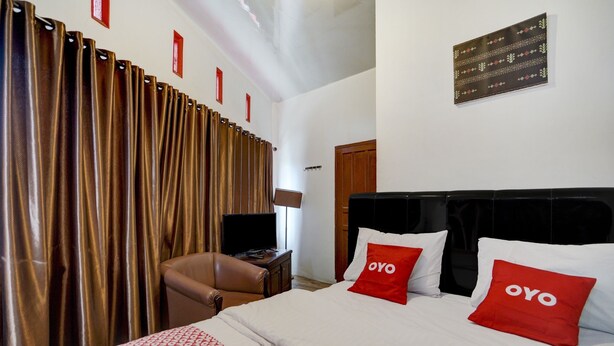 Ein Hotelzimmer mit Bett, Fernseher, Schreibtisch und Stuhl.