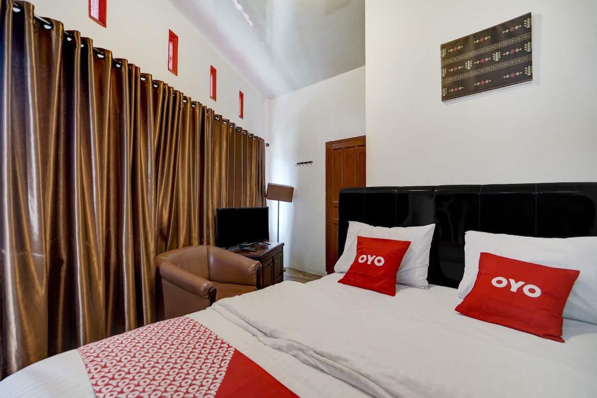 Una habitación de hotel con una cama, televisor, escritorio y silla.