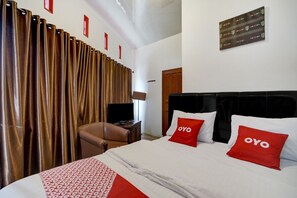 A hotel room with a bed, a television, a desk, and a chair.